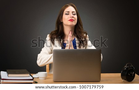 Business woman working with her laptop and in zen position on black background