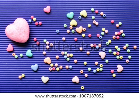 The 14th of February. St. Valentine's Day. Background with multicolored beads balls and hearts on a blue striped background. Top view with copy space