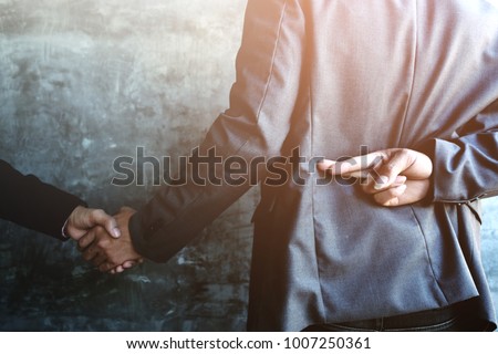 Business people shaking hands and one of them holding fingers crossed behind back, Represents the betrayal. Royalty-Free Stock Photo #1007250361