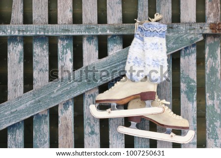 Ice skating female boots, wool knitted mittens on blue aged, weathered wooden fence, winter scene, space and outdoor, really photo, daylight