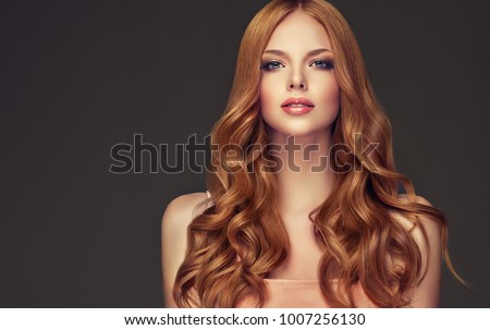 Red head  girl with long  and   shiny wavy hair .  Beautiful  model woman with curly hairstyle .