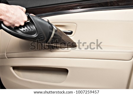 Portable car vacuum cleaner In action. Vacuums the car seats, interior, front pallets, doors. Ready product card. Without a logo. Royalty-Free Stock Photo #1007259457