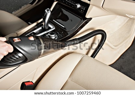 Portable car vacuum cleaner In action. Vacuums the car seats, interior, front pallets, doors. Ready product card. Without a logo. Royalty-Free Stock Photo #1007259460