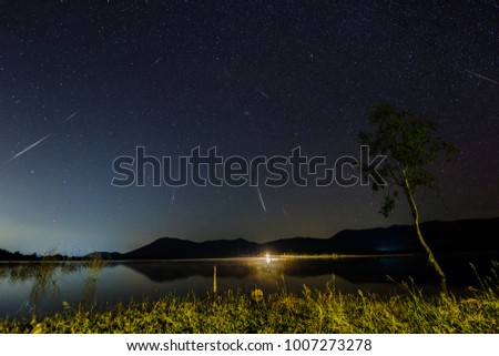 Shooting star over reservoir with mountain night sky.