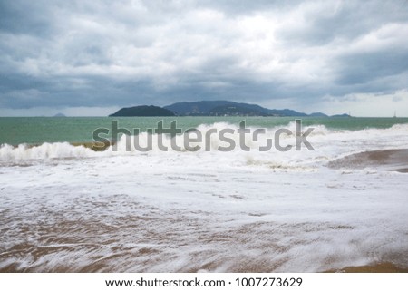 storm with big waves on the seashore with mountains on the background