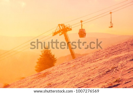Ski lift cabine in ski resort. Sunrise light in background. Orange edit space for your montage.