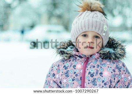 The child is playing with snow during the winter in the afternoo