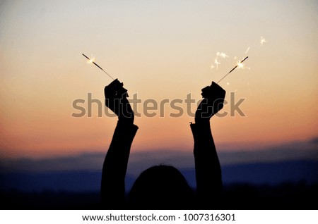 happy holidays.Vintage flim grain Style. Abstract blur  background,woman hand holding a burning sparkler light with purple sky background.closeup in female hand in dark.