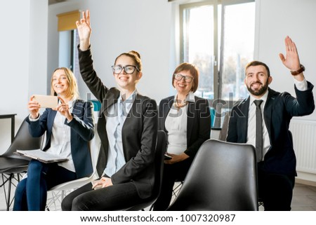 Business people sitting during the conference in the audience raising hands
