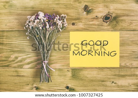 Beautiful bouquet of flowers and  text good morning on wooden table.Image is intentionally toned.