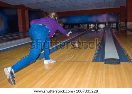 Girl wearing jeans playing bowling.