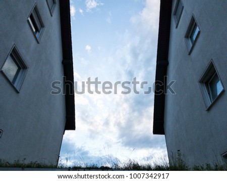 Photo of a view on a beautiful blue cloudy sky between two houses