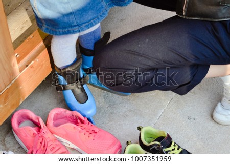 Joyful active mother and her child going ice-skating on outdoors background. Close up on tightening laces, ready changing shoes. Family getting happiness, having fun and sporty lifestyle