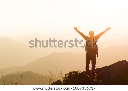 Silhouette of man hold up hands on the peak of mountain,success concept Royalty-Free Stock Photo #1007356717