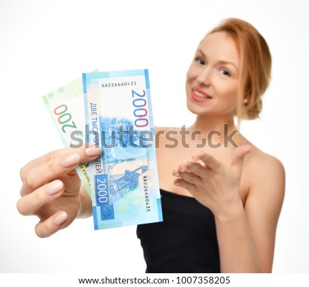 Young woman holding up cash money two thousand and hundred russian rubles notes in hand winner surprised isolated on a white background