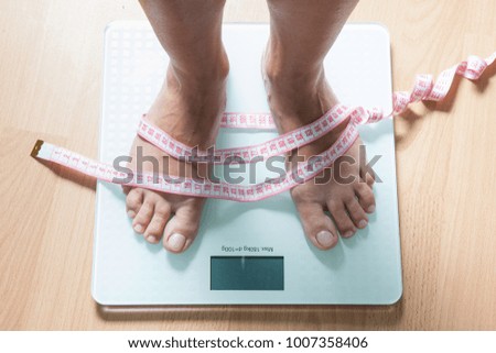 Healthy diet, fitness and weight loss concept. The legs of a young woman on the scales. Measuring tape. Checking the weight.
