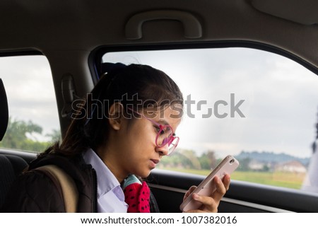Female students wear glasses good play mobile in the car on the road as traffic jams in the morning.