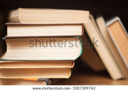 Old and used hardback books or text books seen from above. Books and reading are essential for self improvement, gaining knowledge and success in our careers, business and personal lives 