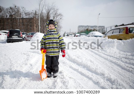 A boy with a shovel cleans the snow
