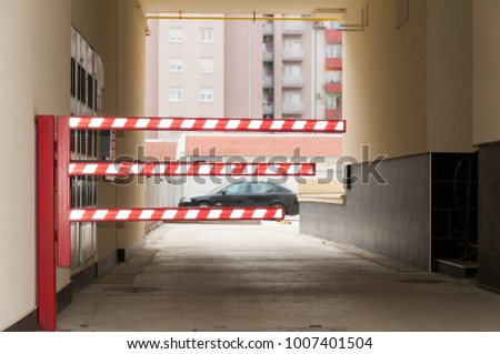 Traffic car barrier with red and white fluorescent reflective light on the entrance of private building parking lot where only tenants can park vehicles