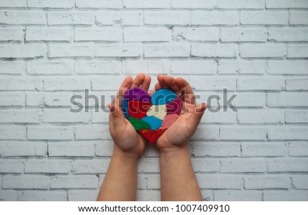 Child's hands holding a heart on white background with text space. World autism awareness day.