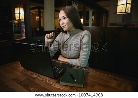 beautiful girl with glasses working in the cafÃ© with a laptop. dreams of a beautiful future