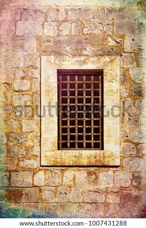 Barred window of traditional stoned house in old Acre. Window in the old city of Akko in Israel. Vintage style toned picture