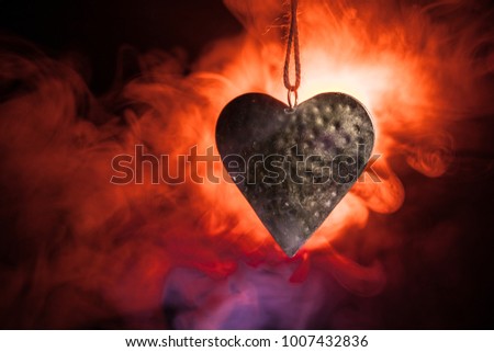 Golden Heart hangs on rope on dark toned smoky background and space for text. Valentine day concept. Selective focus
