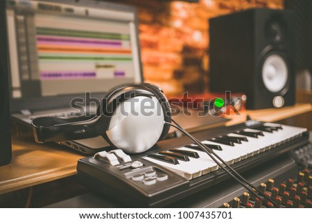 computer music, home studio equipment. headphone on midi keyboard synthesizer with laptop computer and loudspeaker monitor
