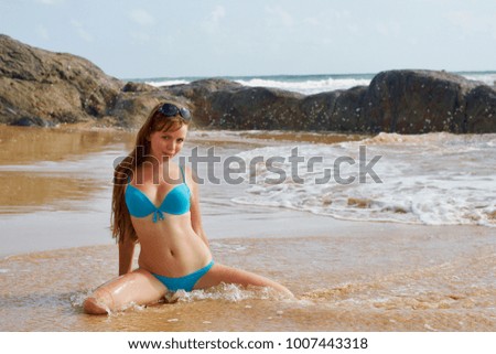 Fair-haired blue-eyed girl in a blue swimsuit on the beach of Bentota, Sri Lanka