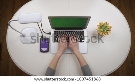 Woman freelancer connected an external hard drive to the laptop and works on it. Chroma key. Top view. Hands close up