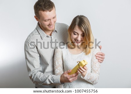 guy in a shirt gives a gift to girl, young couple, congratulates on a Valentine's Day, the concept of a holy Valentine, in a studio on a white background
