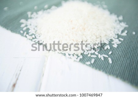 Diet, Organic Food, Vegetarian, Groats Concept. A pile of white rice on a table in a close up, white wood and blue linen cloth as a background