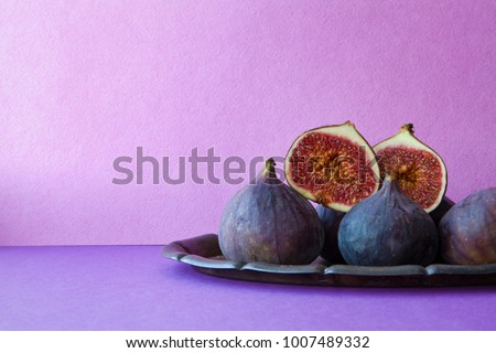 Bright still life organic fig fruits on an old tray, beautiful purple violet background. Selective focus photography, copy space