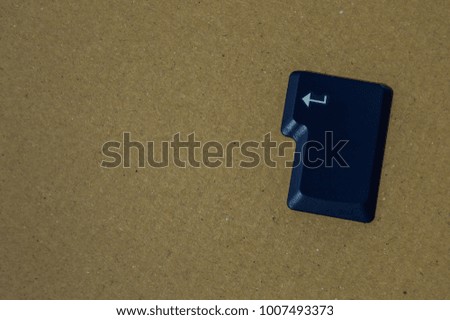 Isolated blue enter key of a computer keyboard. Vintage paperboard background. Concept of start or accept, with place for add text or elements.