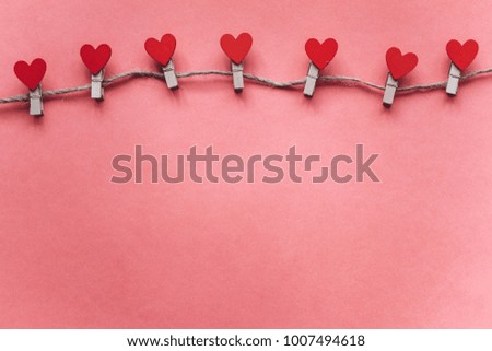 Clothespins in the form of hearts on a pink background.