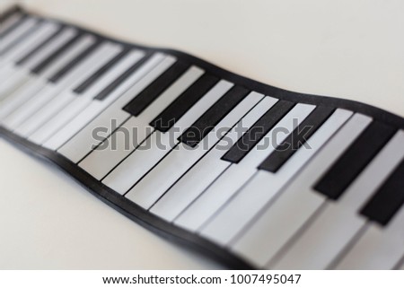 Detail shot of keys of a pocket piano keyboard black and white on a white table background, music learning concept, musicology images. Musical production concept.