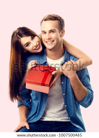 Happy couple with gift box, close to each other and looking at camera with smile. Caucasian models in love, relationship, dating, flirting, lovers, romantic concept.