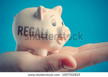 Piggy bank in a human hand with inscription GIFTS on a blue background