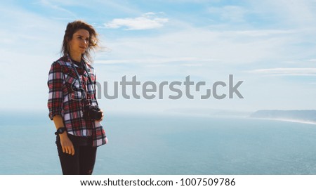 Tourist traveler photographer making pictures sea scape on photo camera on background ocean, hipster girl looking on nature horizon, relax holiday, blank space blue waves view, backdrop for text