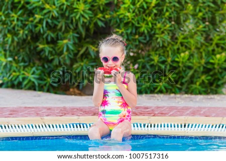 Child eating watermelon outdoor. Kid having fun in swimming pool. Summer vacation and healthy lifestyle concept