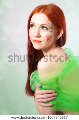 Portrait of beautiful red-haired girl with a flower painted on his face
