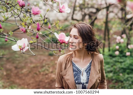 Beautiful caucasian woman in blossom magnolia garden. 