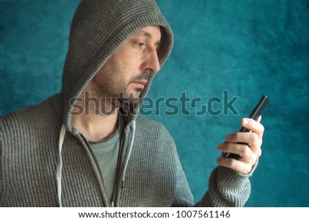 Casual man looking at mobile phone screen and reading app notification or sms text message