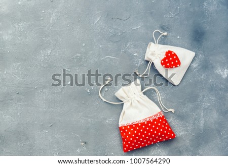Gifting theme image with a checkered fabric pouch and a decorative red heart over vintage background