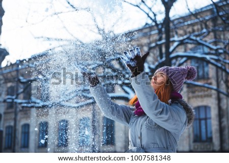 Happy redhead woman walking in winter park and enjoy the snow. Concept picture