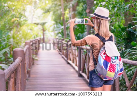 Travelling concept. Photographing adventure. Young woman taking picture on her smartphone in jungle.