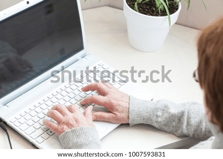 Cropped image. Senior woman at home we bsurfing on laptop computer