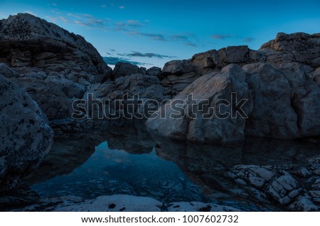 Beautiful details of rocks and stones at Adriatic Sea in Croatia Europe. Nice, calm summer evening with still water and reflections. Blue cool tones at dusk. Peaceful background image.