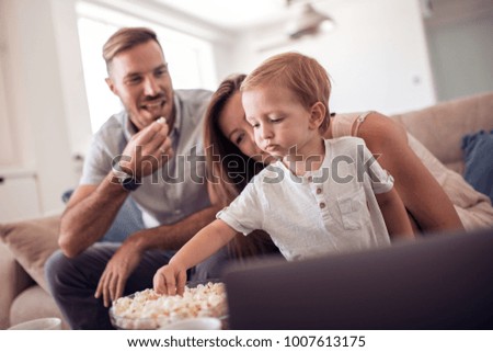 Portrait of a joyful family using a laptop sitting on sofa at home.